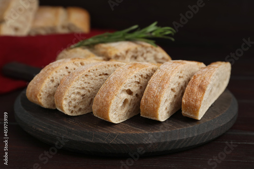 Board with cut delicious ciabatta on wooden table