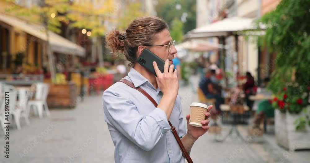 Caucasian man drinking coffee in town on street and chatting with somebody at the smartphone outdoors. Young male using his gadget. Leisure concept Caucasian man drinking coffee in town on street and chatting with somebody at the smartphone outdoors. Young male using his gadget. Leisure concept
