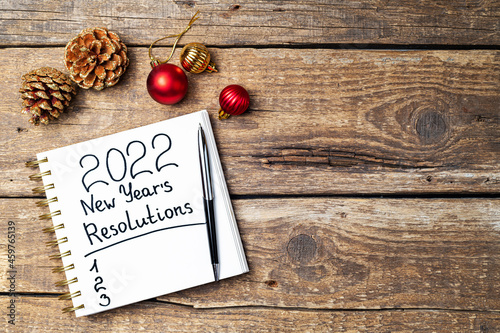 New year Resolutions 2022 on desk. 2022 Resolutions with open notebook, Christmas ornaments on wooden background. Goals, plan, strategy, action, idea concept. New Year 2022, copy space