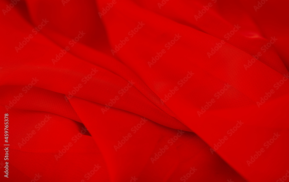 Red chiffon or silk material. Satin fabric close up background and texture with place for text. blurred background.