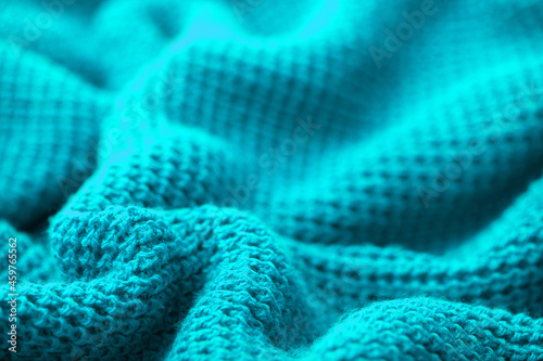 Knitted fabric turquoise surface as a background, winter scarves, blue warm plaid. Beautiful bright autumn clothes. Sewing and knitting.