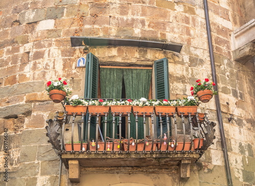 An elegant wrought-iron balcony of an old medieval house decorated with flowers
