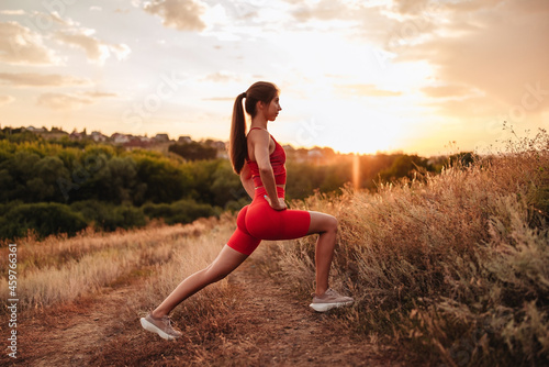 Fitness woman ready for running at sunset or sunrise on beach. Female athlete in powerful starting line pose.