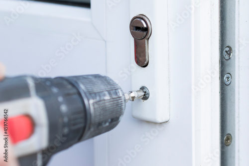 Handyman check door lock with screw gun in front door. Checking lock for operability close up.