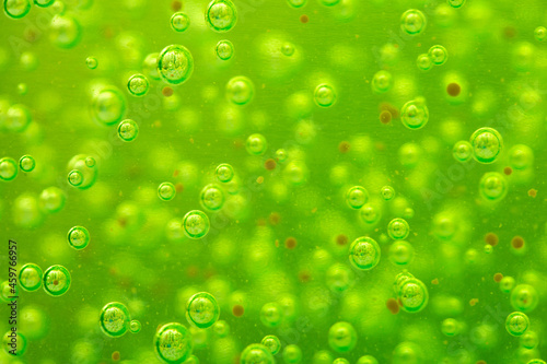 Liquid with bubbles. Green body scrub close-up, particles of exfoliating ingredients, bubbles. Shower gel, cleansing the face and body. Spa treatments, skin care.
