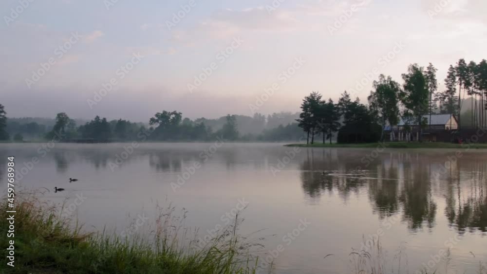 Beautiful sunrise at lake surrounded by forest. Morning fog floating over water surface. Birds singing in the background. Krasnobród, Roztocze, Poland.