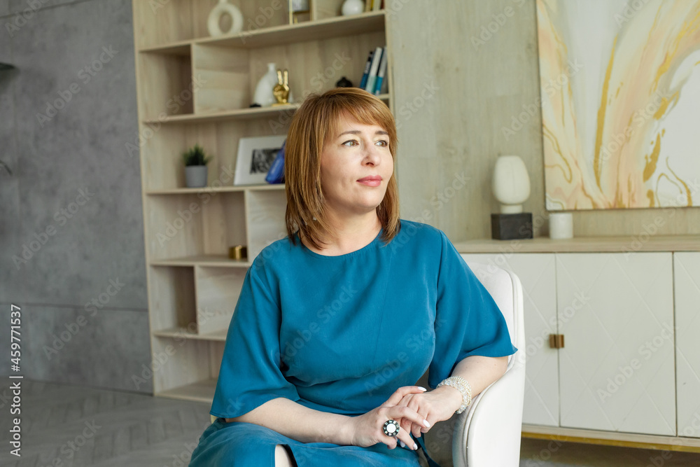 Positive middle-aged woman sitting on armchair at home Positive middle-aged woman sitting on armchair at home
