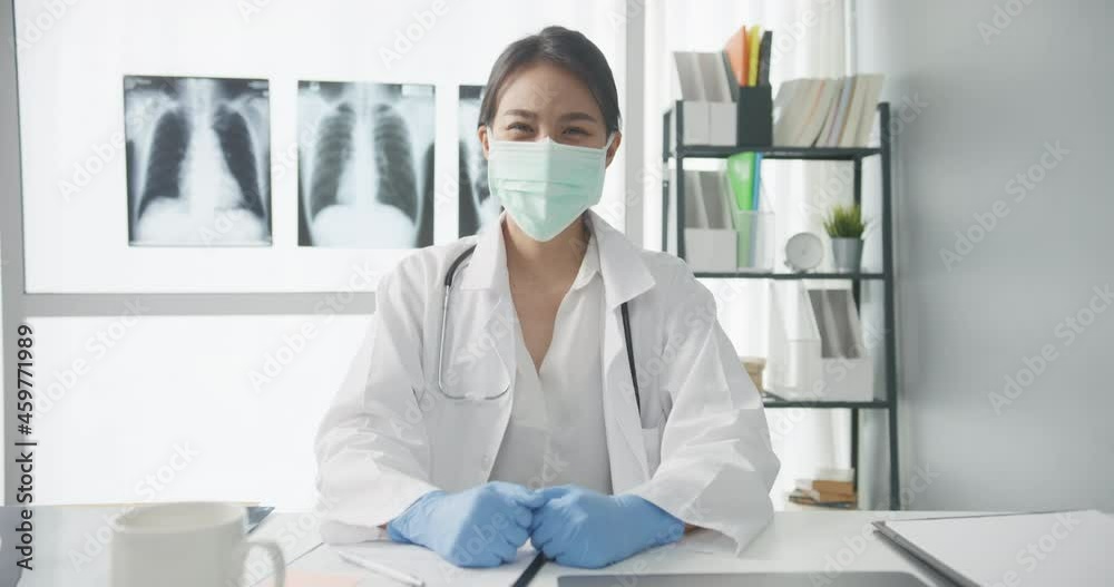 Confident young Asia female doctor wear protective mask with stethoscope looking at camera and smiling while video conference call with patient in health hospital. Consulting and therapy concept. Confident young Asia female doctor wear protective mask with stethoscope looking at camera and smiling while video conference call with patient in health hospital. Consulting and therapy concept.