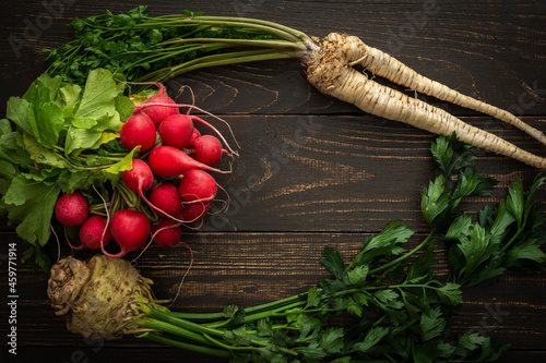 Root vegetables with green leaves on a wooden background, radish with parsley root and celera, farm vegetables photo