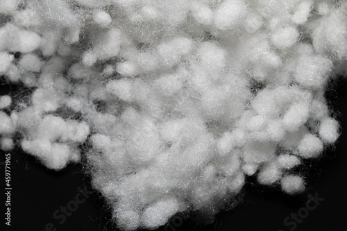 Synthetic fiber, polyester fiber, white synthetic winterizer on a black background,  siliconized holofiber. Close-up. It is used as a filler for blankets, pillows, clothes and upholstered furniture. photo