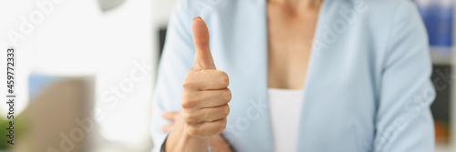 Businesswoman in suit holds thumbs up in office photo