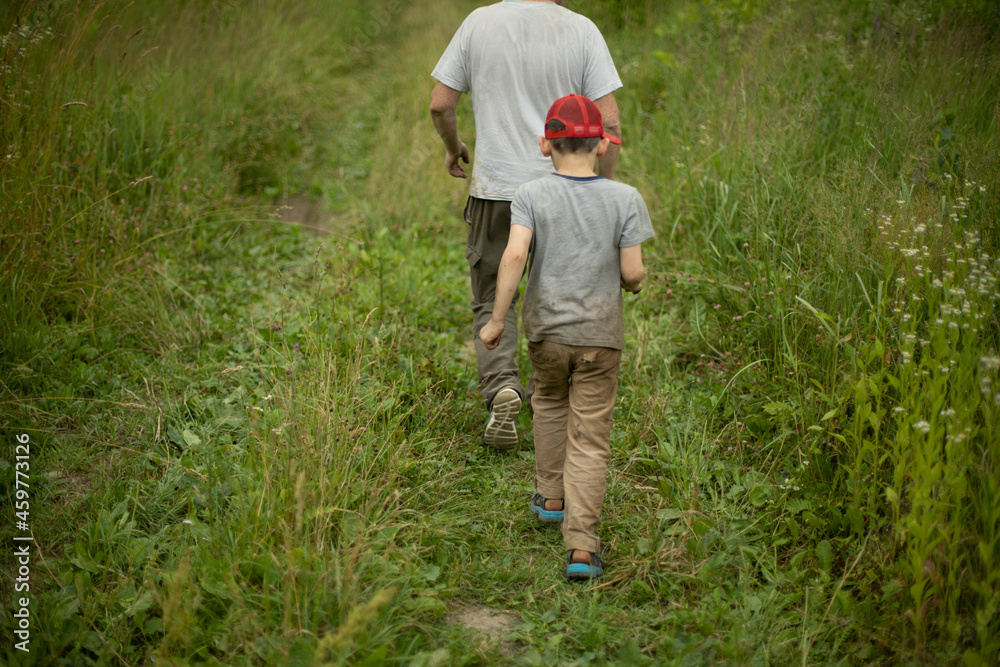 The child walks with his father across the field. Man among plants. The child walks with his father across the field. Man among plants.