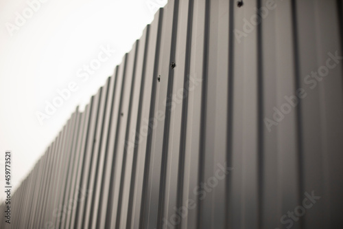 Grey fence made of metal. Solid high fence. Profiled metal is used in the fence of private territory. © Олег Копьёв