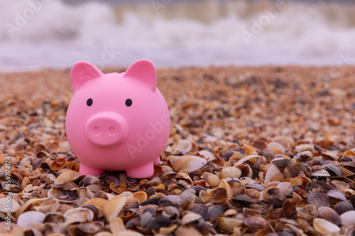 Vacation savings concept. piggy bank on the beach on a background of waves with copy space.