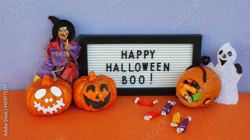 Halloween concept. Decoration on the table with sweets and halloween accessories. A frame with the text happy halloween boo.