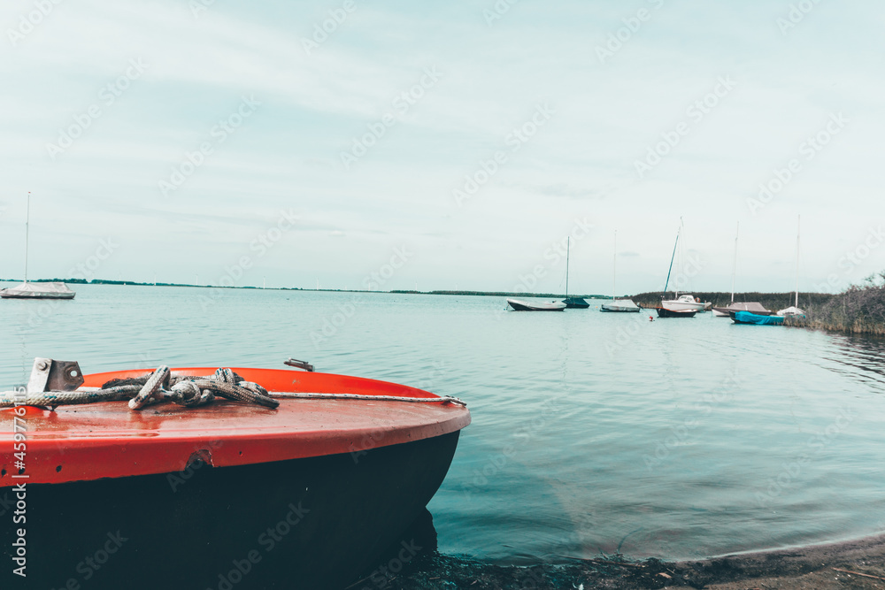 Fototapeta premium A wooden boat stands on the bank of the river. Walking on the water. Boat on the beach in summer by the river. Summer vacation on the water with a boat.