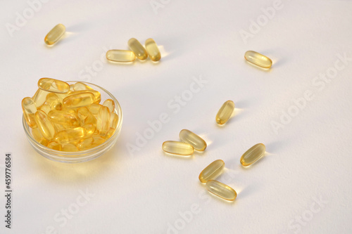 yellow fish oil capsules scattered on white background