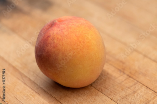 A single ripe Angelus peach on wooden carving board 