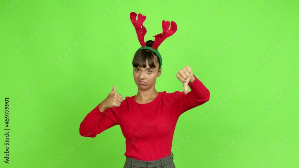 Young woman wearing christmas hat making good-bad sign over isolated background. Green screen chroma key Young woman wearing christmas hat making good-bad sign over isolated background. Green screen chroma key