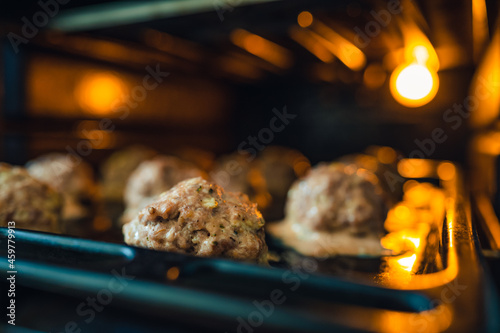 View into the oven on the baking tray for meatballs. Little light, light only from the oven. Shallow depth of field, blurred background. photo