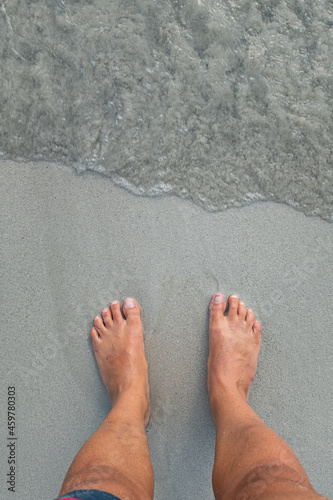 Feet on the grey sand of a beach shore