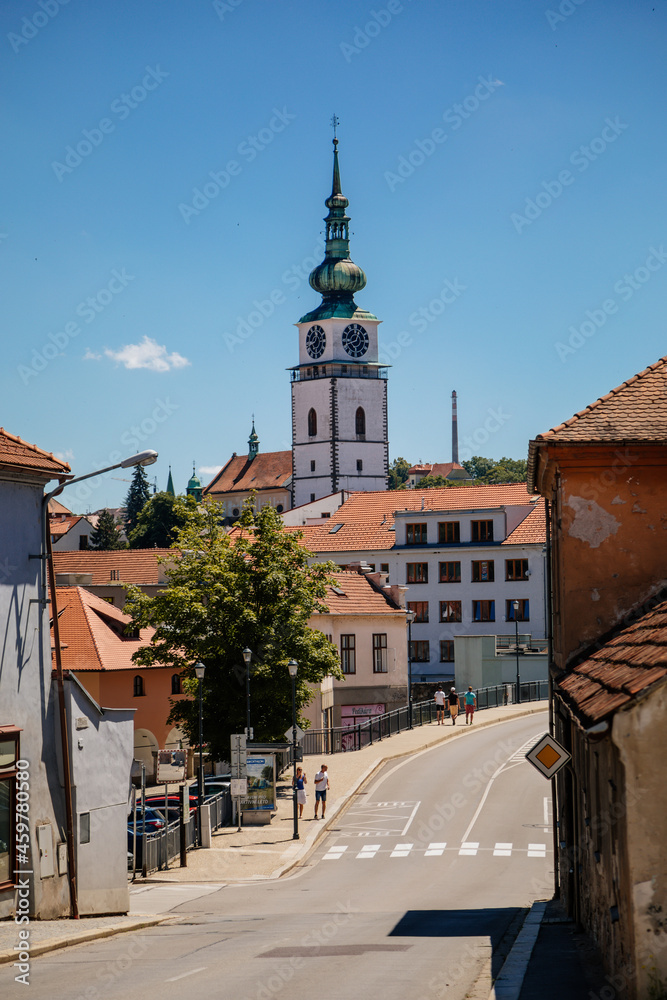 Fototapeta premium Trebic, Bohemia, Czech Republic, 06 July 2021: Narrow picturesque street with colorful buildings in historic center, renaissance and baroque medieval city, Church of St. Martina at sunny summer day
