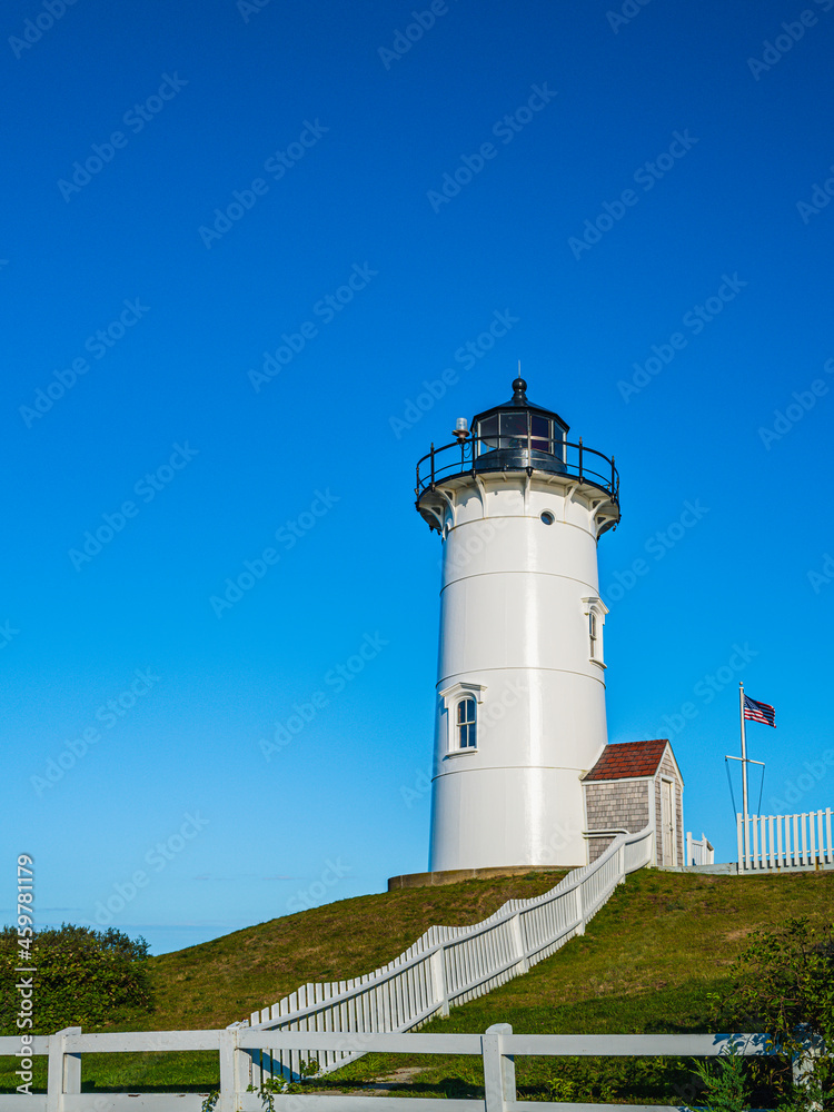 White lighthouse on the hill against the clear blue sky background