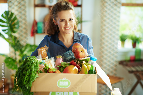 smiling modern woman with food box in kitchen