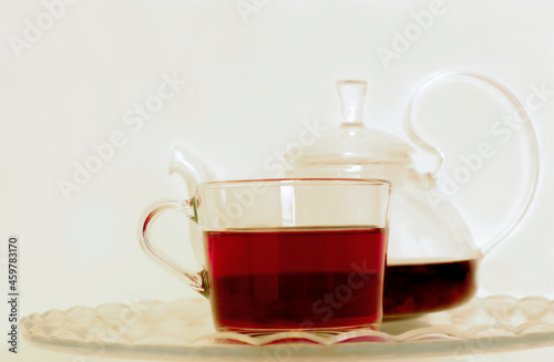 tea in a transparent mug with a teapot on a light background