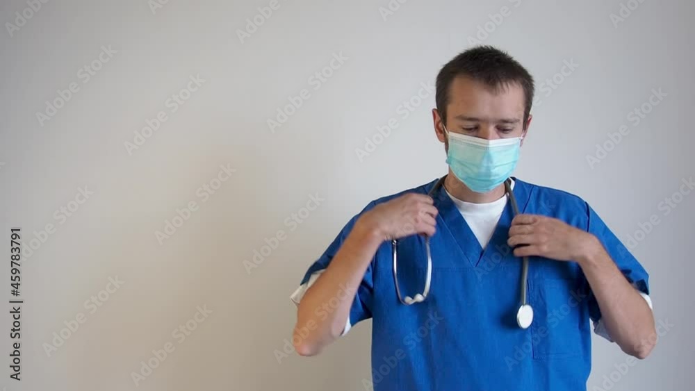 Serious tired doctor man in medical mask looking at camera and taking off mask medical and stetoskop and do away. Copy space for text 