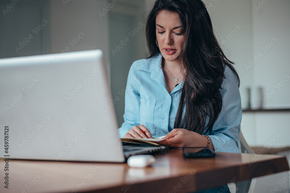 Businesswoman using a laptop and a business planner in an office Businesswoman using a laptop and a business planner in an office