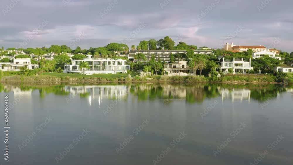 Drone flying over Quinta do Lago with surrounded hotels, Algarve, Portugal, Europe. Panoramic shot of luxury houses located at beachfront of lake. Green trees growing around, 4k footage Drone flying over Quinta do Lago with surrounded hotels, Algarve, Portugal, Europe. Panoramic shot of luxury houses located at beachfront of lake. Green trees growing around, 4k footage