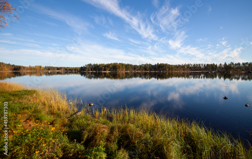 Blue cloudy sky over blue lake on warm autumn day