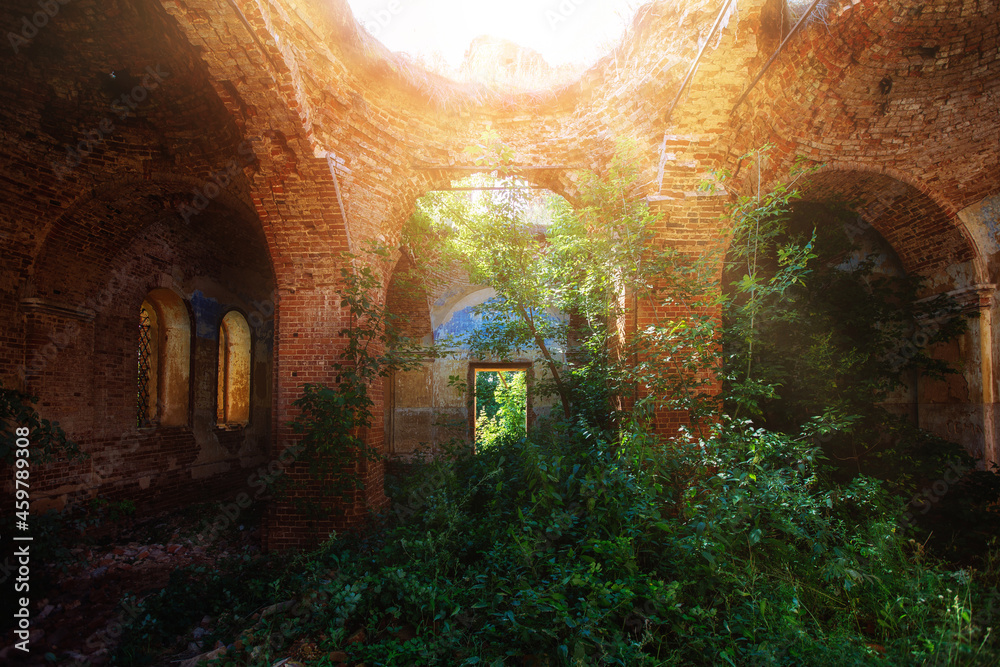 Old ancient abandoned red brick ruins overgrown by plants.