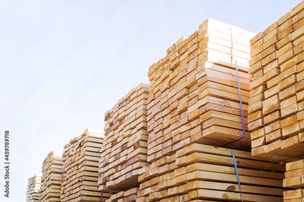 Stacked stacks of wooden planks against the sky. Lumber warehouse, wood drying. Lumber for construction. Stacked stacks of wooden planks against the sky. Lumber warehouse, wood drying. Lumber for construction.