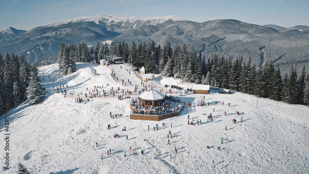 Winter sport resort with ski slope aerial. Snow mountain nature landscape. Tourists extreme sport and recreation. People rest at snowy mount top. Cinematic Carpathians, Bukovel, Ukraine, Europe