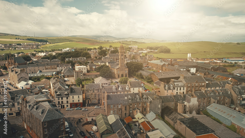 Sun cityscape at traffic road cars drives aerial. Historic buildings at streets of Campbeltown city, Scotland, Europe. Downtown houses and architecture landmark. Cinematic sunlight urban scenery