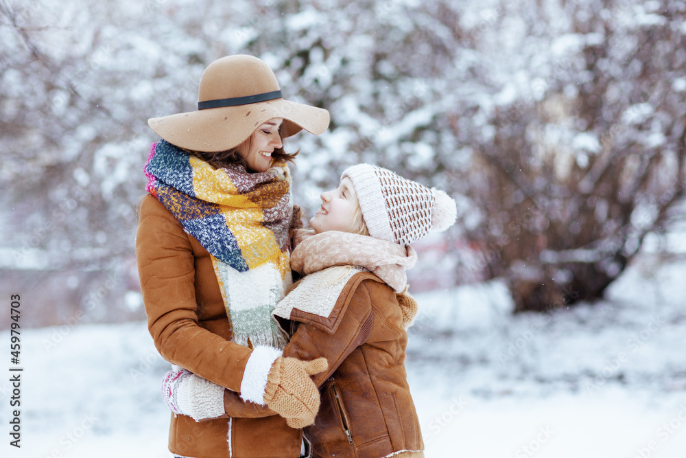 Fototapeta premium happy mom and child hugging outside in city park in winter