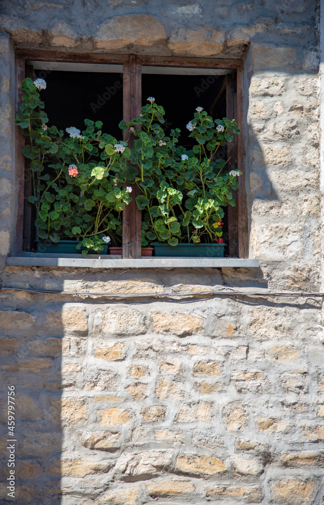 A window in the stone wall, decorated with pots of blooming geraniums. A window in the stone wall, decorated with pots of blooming geraniums.