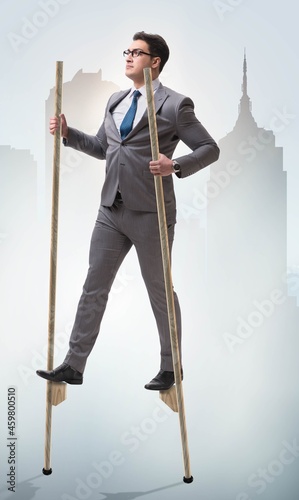 Businessman walking on stilts - standing out from the crowd photo