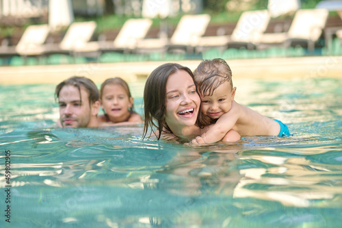 A young family having fun in a pool and looking enjoyed