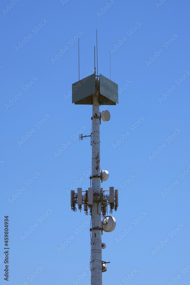 Low angle view of the top of a communication antenna tower under blue sky
