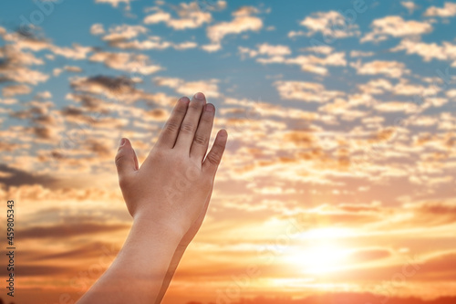 Praying hands with faith in religion and belief in God over blur sunset sky background.