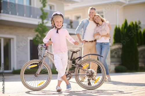 Confident girl with bike and happy parents