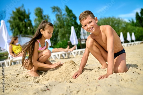 Two kids playing with sand on a beach