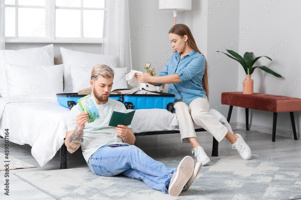 Fototapeta premium Couple of tourists packing suitcase at home