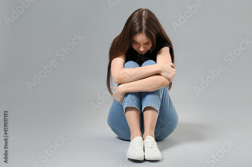 Scared young woman on grey ...