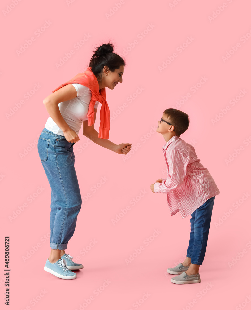 Dancing young woman and her little son on color background