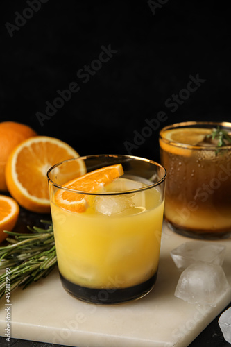 Glasses of tasty coffee with orange juice on dark background