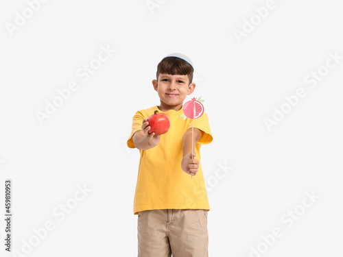 Little boy with pomegranate and decor for Rosh Hashanah (Jewish New Year) on white background